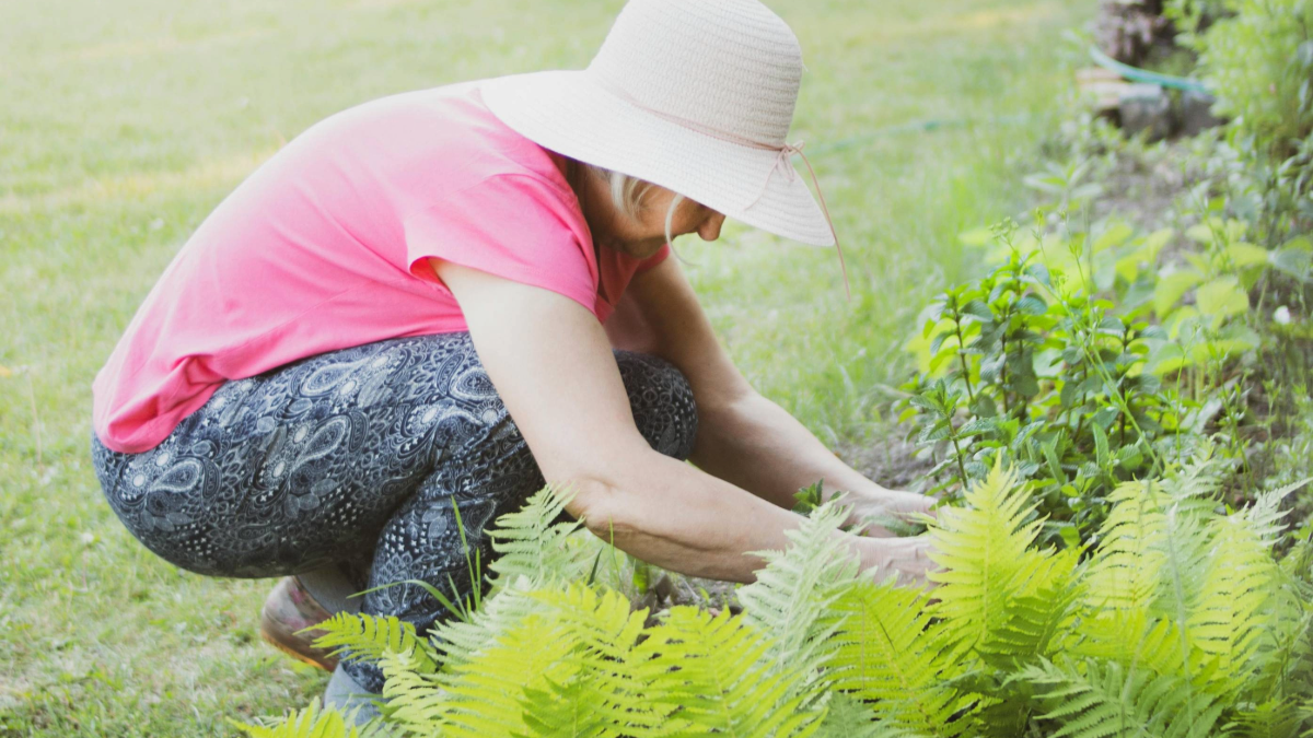 Woman gardening outside in sun and heat protective gear